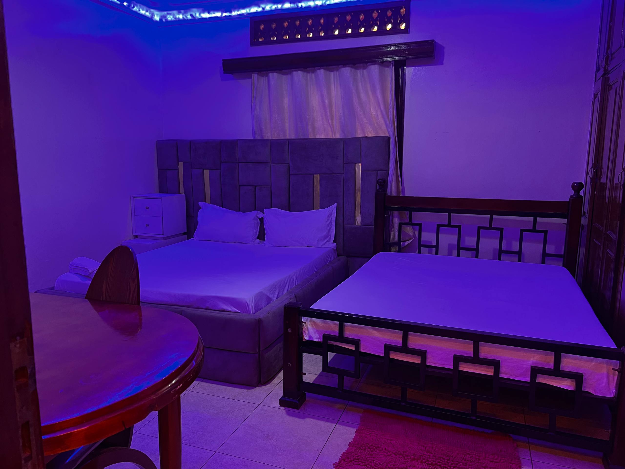An Eden guest room with white linens and blue ambient lighting